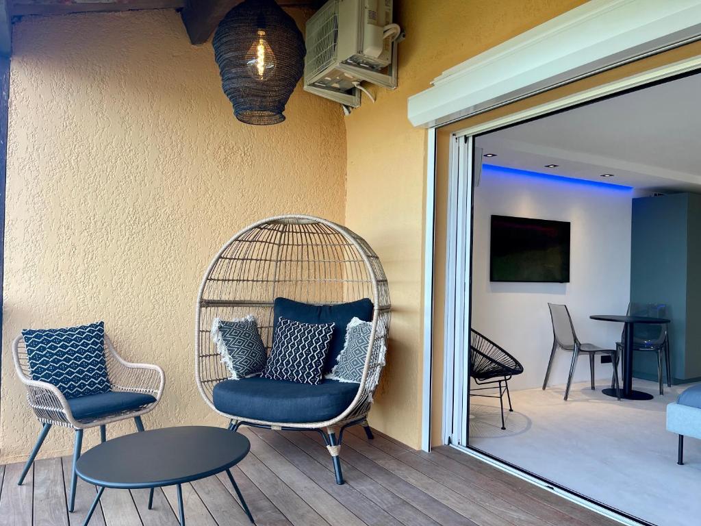 a room with chairs and a rattan chair and a table at Appartement neuf climatisé - vue mer Saint-Tropez - 50m plage et port - piscine in Gassin