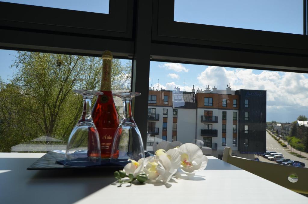 - une table avec deux bouteilles et des fleurs devant une fenêtre dans l'établissement Apartament Mili, à Międzyzdroje