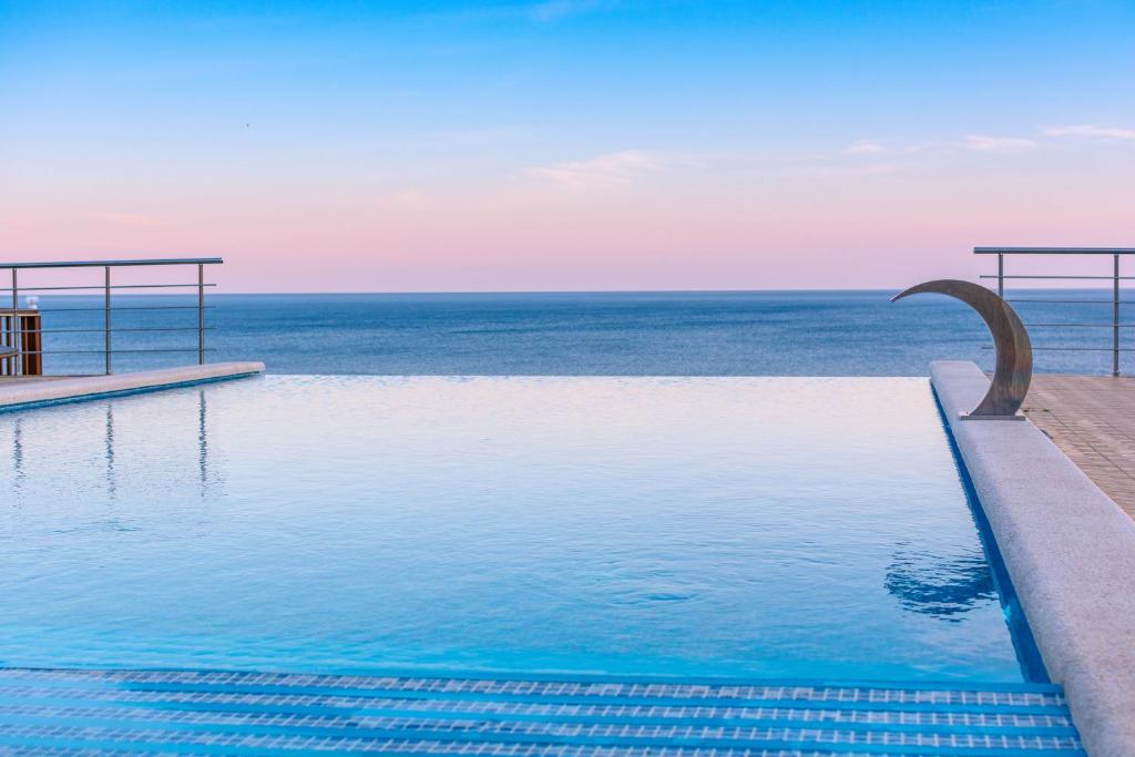 a swimming pool with the ocean in the background at Complex Grand Paradise Hotel in Dzhubga