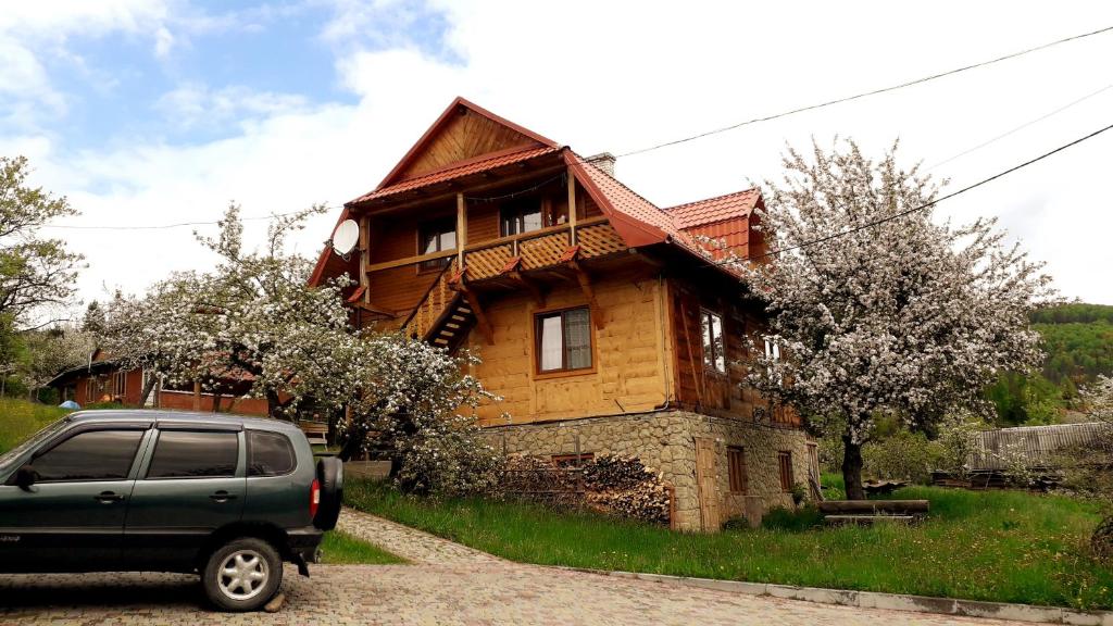 a car parked in front of a wooden house at Садиба "Три Царі" in Yaremche