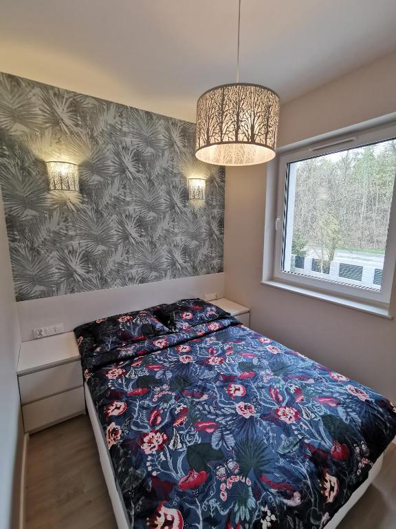 a bedroom with a bed with a floral comforter and a window at M&K Apartament Nadmorski Zagajnik - Sobieszewo, Wyspa Sobieszewska in Gdańsk