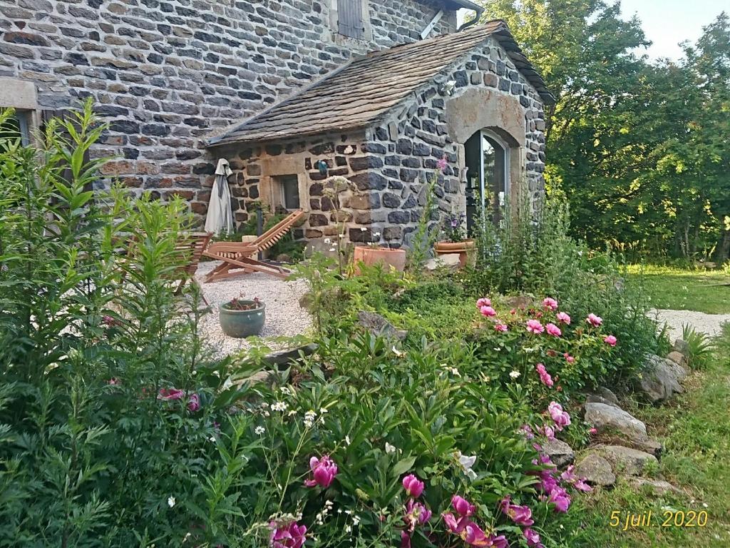 - un bâtiment en pierre avec un banc et quelques fleurs dans l'établissement Bastides Du Mezenc, à Saint-Front