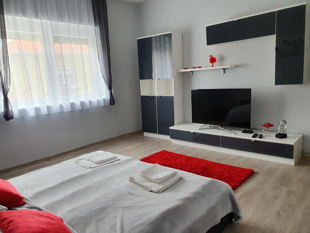 a bedroom with a bed with a red rug at Flamingo Apartment in Sárvár