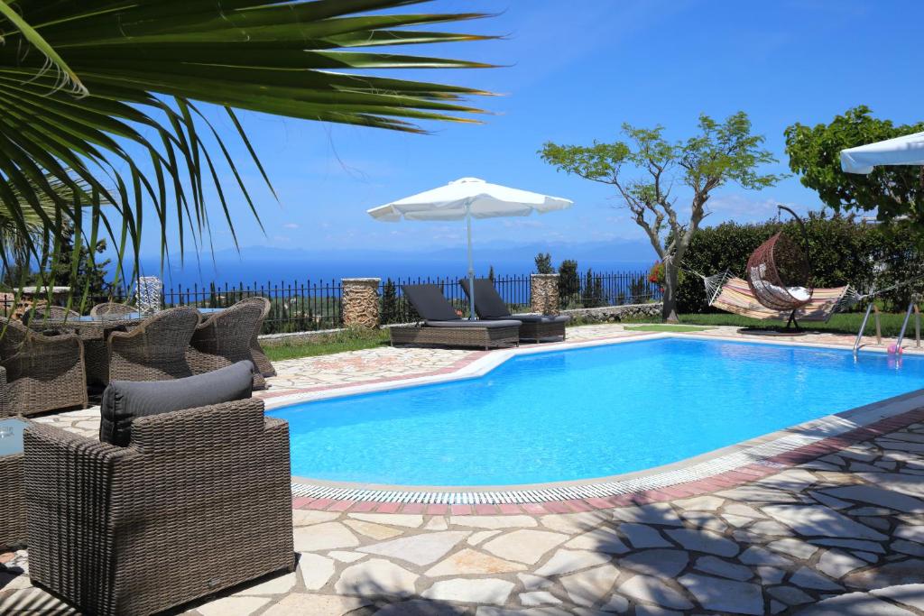 a swimming pool with chairs and an umbrella at Villas Goudis in Tsoukaladhes