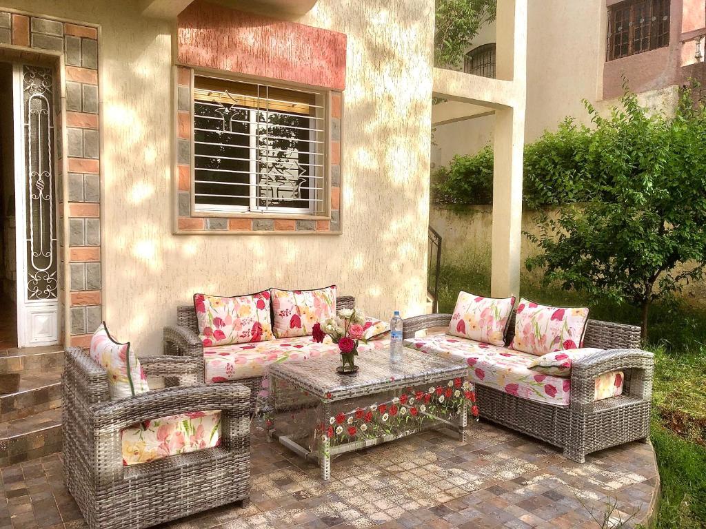 a patio with two wicker couches and a table at Villa ain soltan in Imouzzer du Kandar
