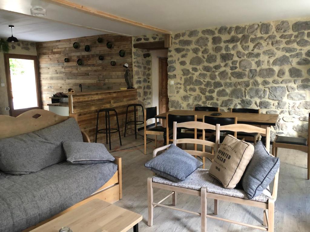 ein Wohnzimmer mit einem Sofa und einer Steinmauer in der Unterkunft Appartement 6 personnes valgorge in Valgorge