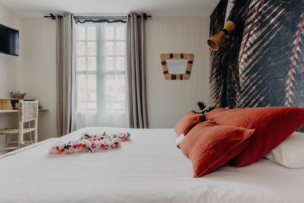 a bed with red pillows and flowers on it at Hôtel PALMITO in Biarritz