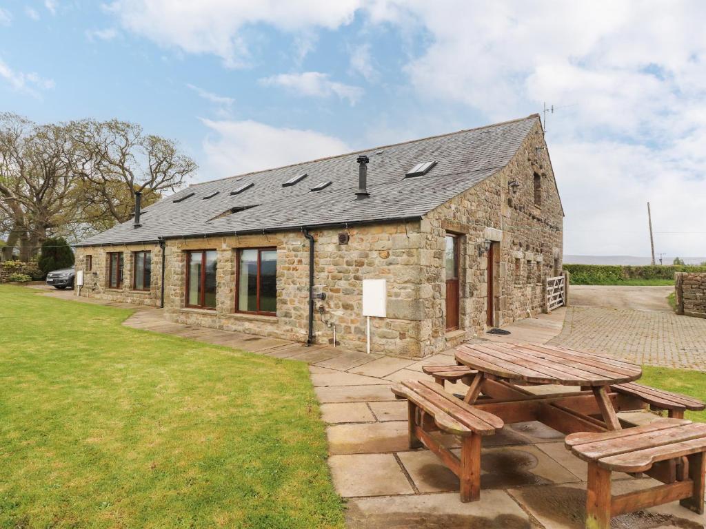 a stone building with two picnic tables in front of it at Ingleborough Barn in Lancaster