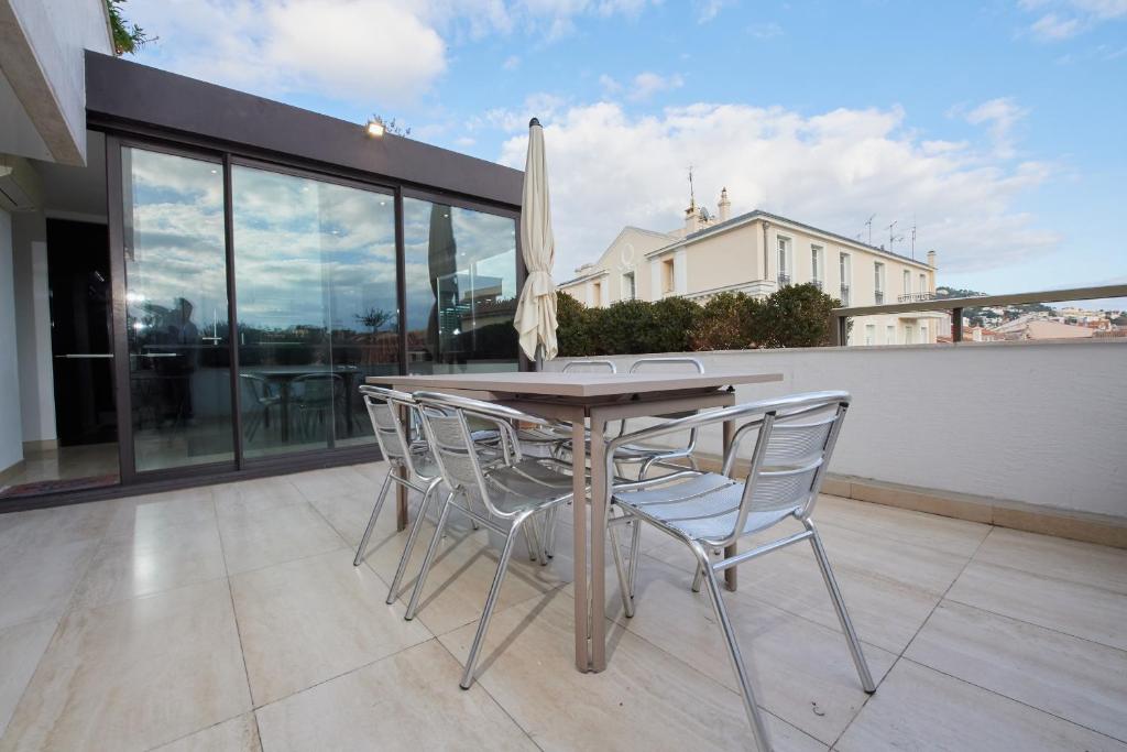 une table et des chaises en bois sur un balcon dans l'établissement Appartement privé vue mer Cannes centre Gray d'Albion, à Cannes