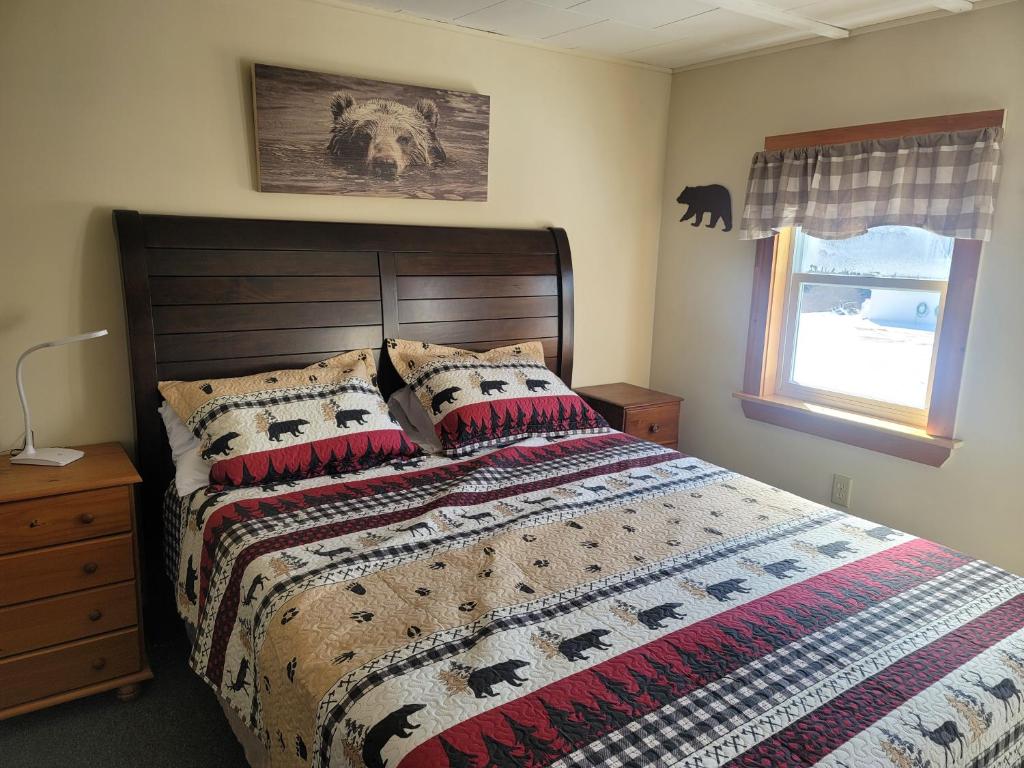 a bedroom with a bed with a blanket and a window at Ladd Pond Cabins and Campground, LLC in Colebrook