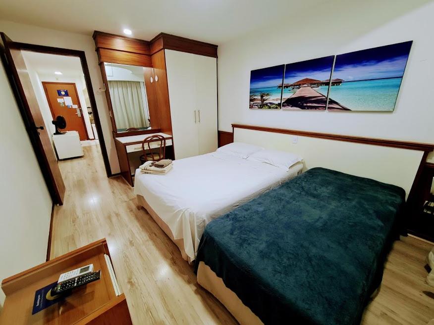 um quarto com uma cama e uma secretária com um comando em Flat Pasárgada 812, Free Bikes, pé na praia em Vila Velha