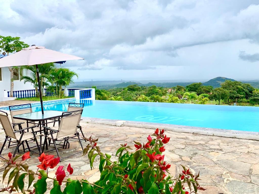 a table with chairs and an umbrella next to a swimming pool at Hotel Eclipse, Playa Coronado in Playa Coronado