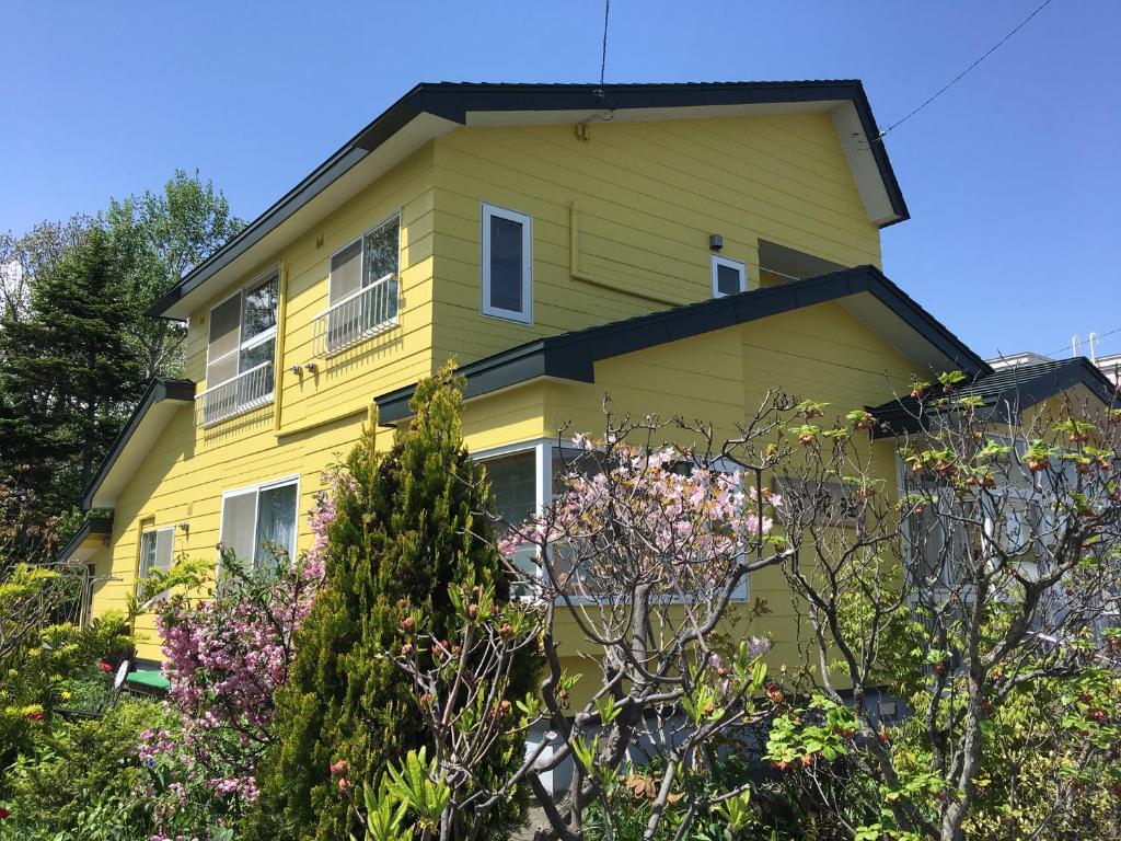 a yellow house with trees in front of it at Koukaso in Eniwa