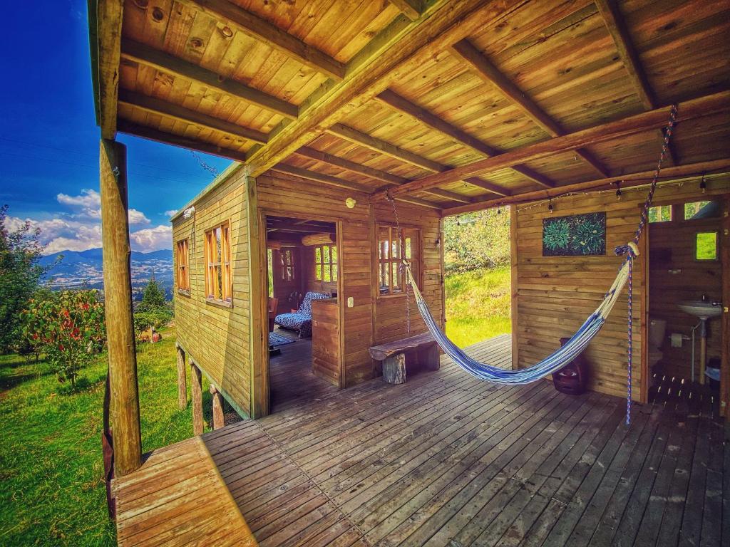 a porch of a wooden cabin with a hammock at Cabaña Agrreste in Nemocón