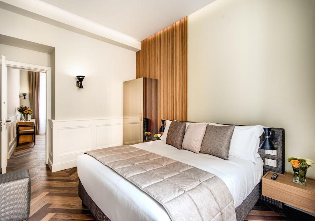 una camera d'albergo con un grande letto e una scrivania di DBH – Boutique Hotel Lake Como a Como
