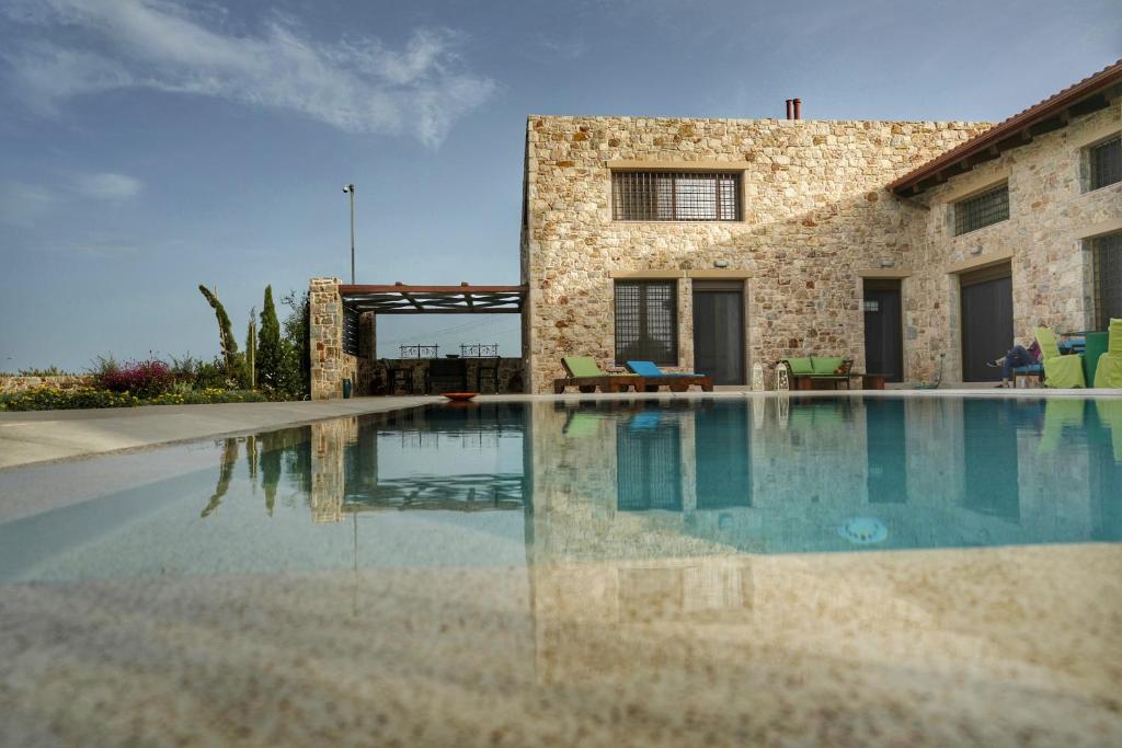 a swimming pool in front of a stone house at Villa Evinoi in Pallini