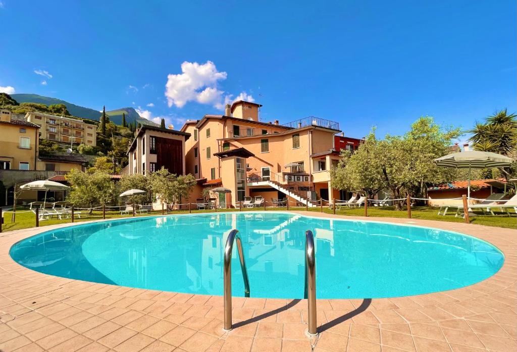 a large swimming pool in a resort with buildings in the background at Albergo Vittoria in Toscolano Maderno