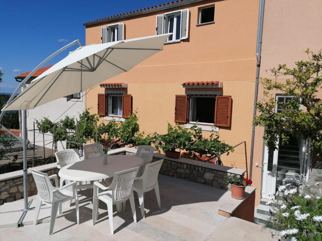a patio with a table and chairs and an umbrella at Apartment Luka in Mali Lošinj