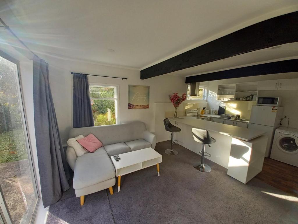a living room with a couch and a kitchen at Lemon Tree Apartment Tawa in Wellington