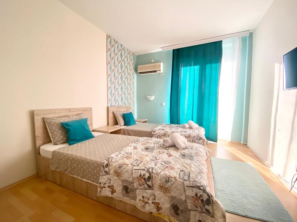 a bedroom with two beds and blue curtains at Hotel Park in Negotino