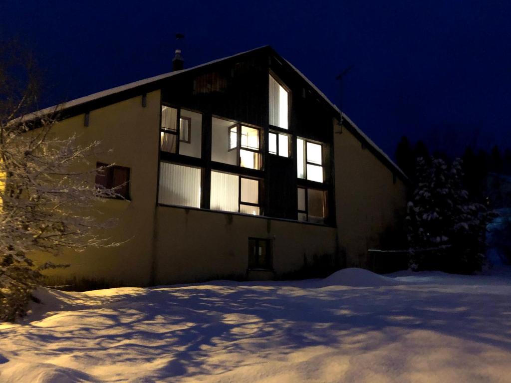 un bâtiment dont les lumières sont allumées dans la neige la nuit dans l'établissement Gîte comme à la maison -12 pers- La Cabiote, à Les Piards