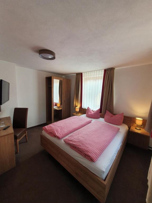 a bedroom with a large bed with pink sheets at Gasthof Alte Schreinerei in Rothenburg ob der Tauber