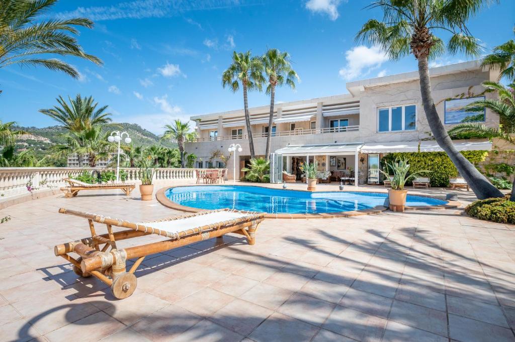 uma vista exterior de uma casa com piscina e palmeiras em Villa Quesada em Paguera