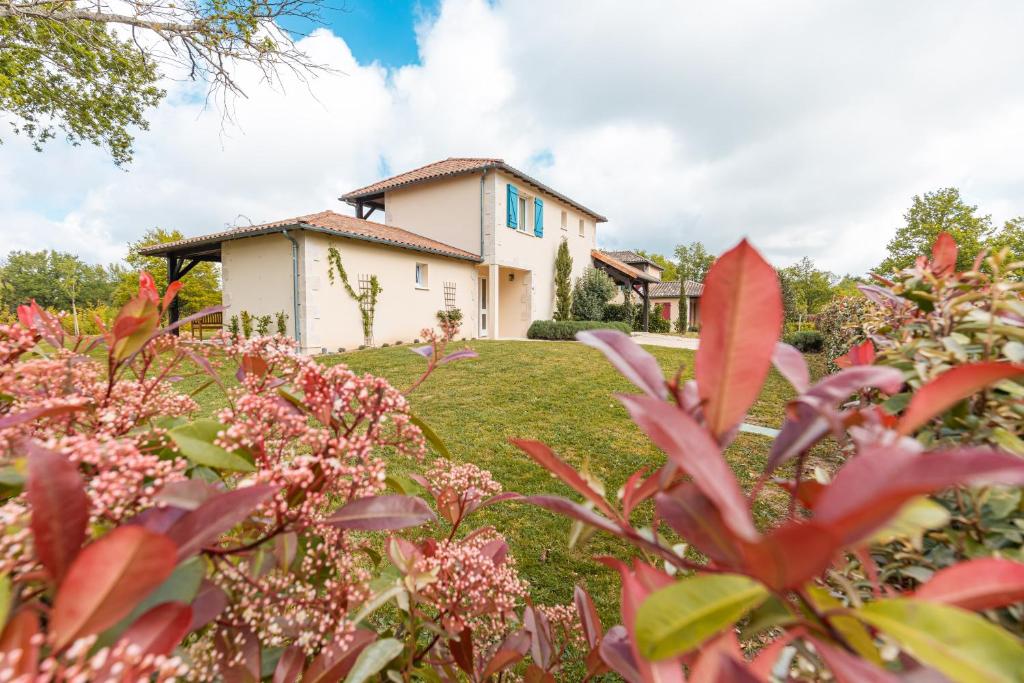 ein Haus im Hintergrund mit Blumen im Vordergrund in der Unterkunft Les Forges Villas - 4 room villa for 8 people in Vasles