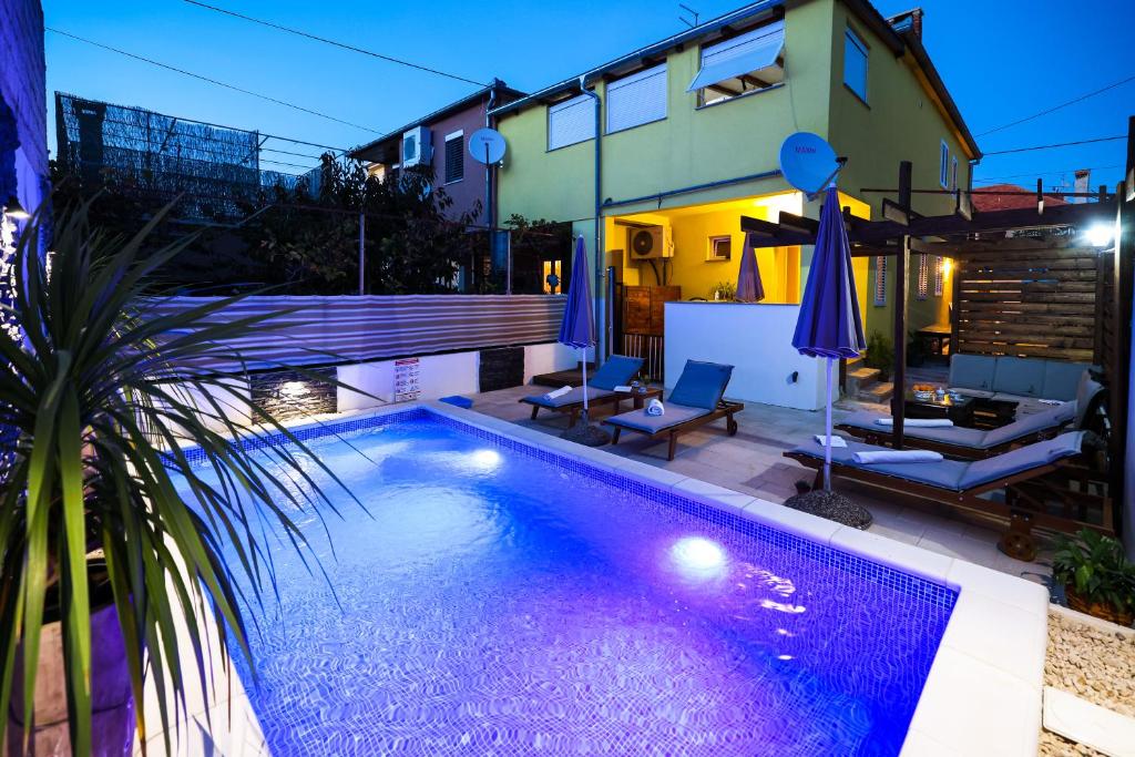 a swimming pool in front of a house at night at Apartment Rustica Zadar with exclusive use of the pool-ground floor in Zadar