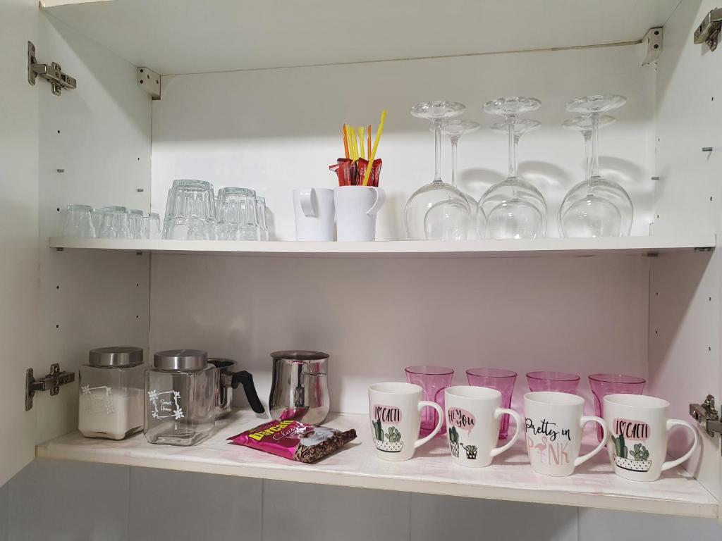 une étagère avec des tasses et des verres dessus dans l'établissement Apartment TIAN, à Koper