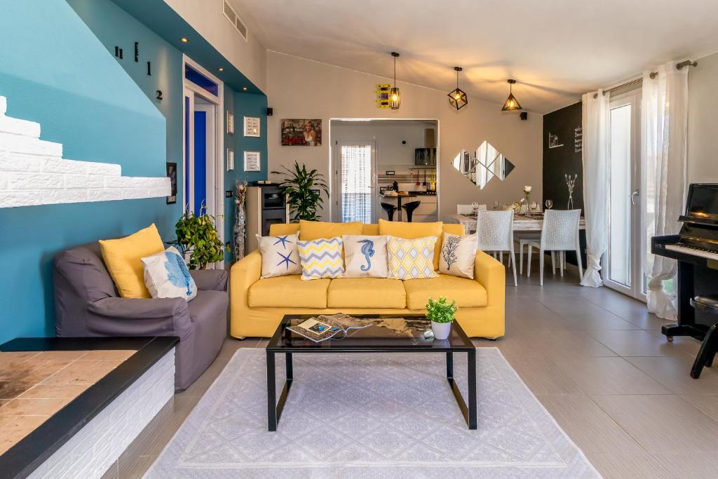 een woonkamer met een gele bank en een tafel bij Sunset Bay Tecno Home Sardinia in Valledoria