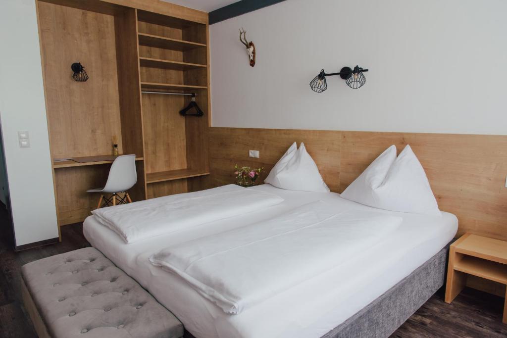 a bedroom with a large white bed and a chair at Hotel Drei Kreuz - Self Check In in Salzburg