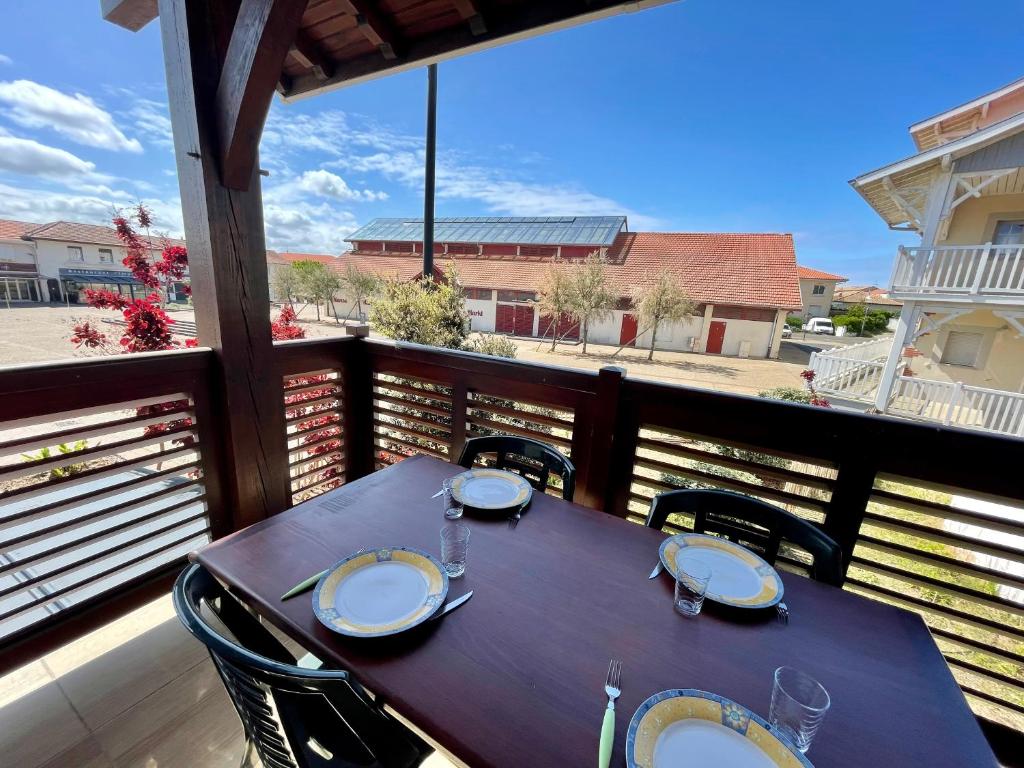 - une table sur un balcon avec vue sur la rue dans l'établissement Les forestiers 2, à Mimizan