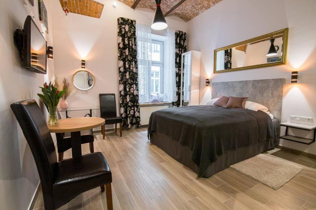 a bedroom with a bed and a table and a desk at Rose - Apartamenty Kleparskie in Krakow
