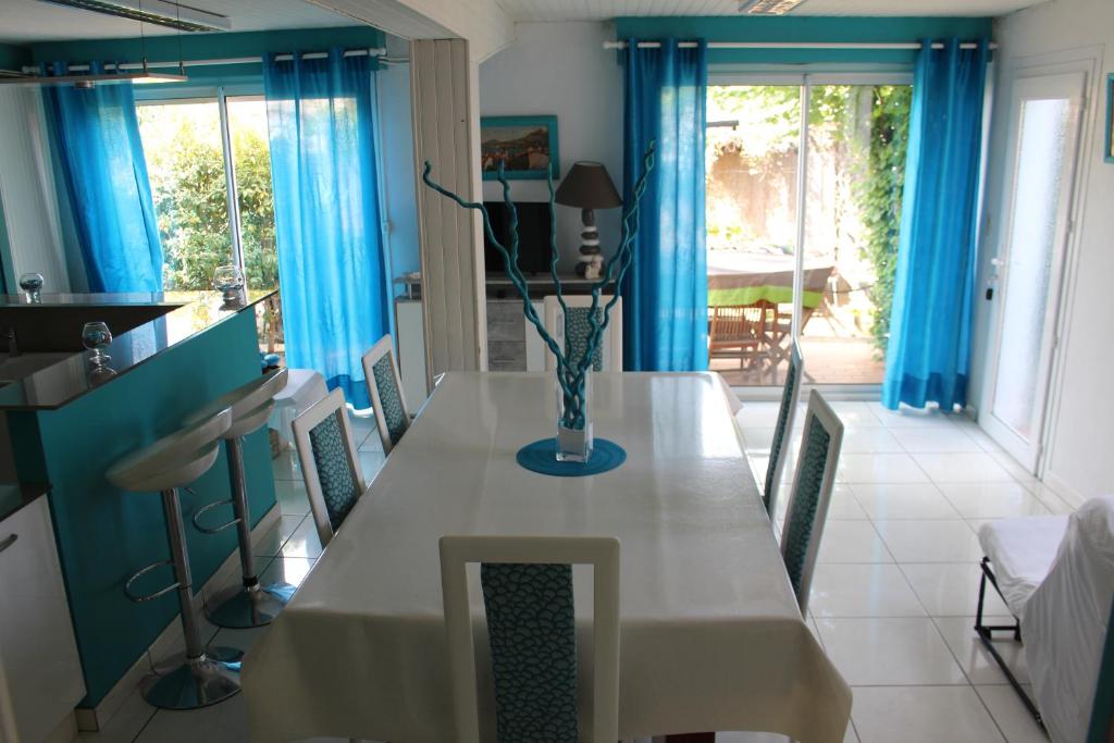 ein Esszimmer mit einem langen Tisch und blauen Vorhängen in der Unterkunft Appartement Annie LLENSE in Argelès-sur-Mer