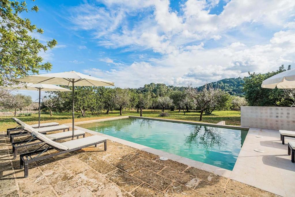 - une piscine avec 2 chaises et un parasol dans l'établissement Villa Empaltada, à Selva