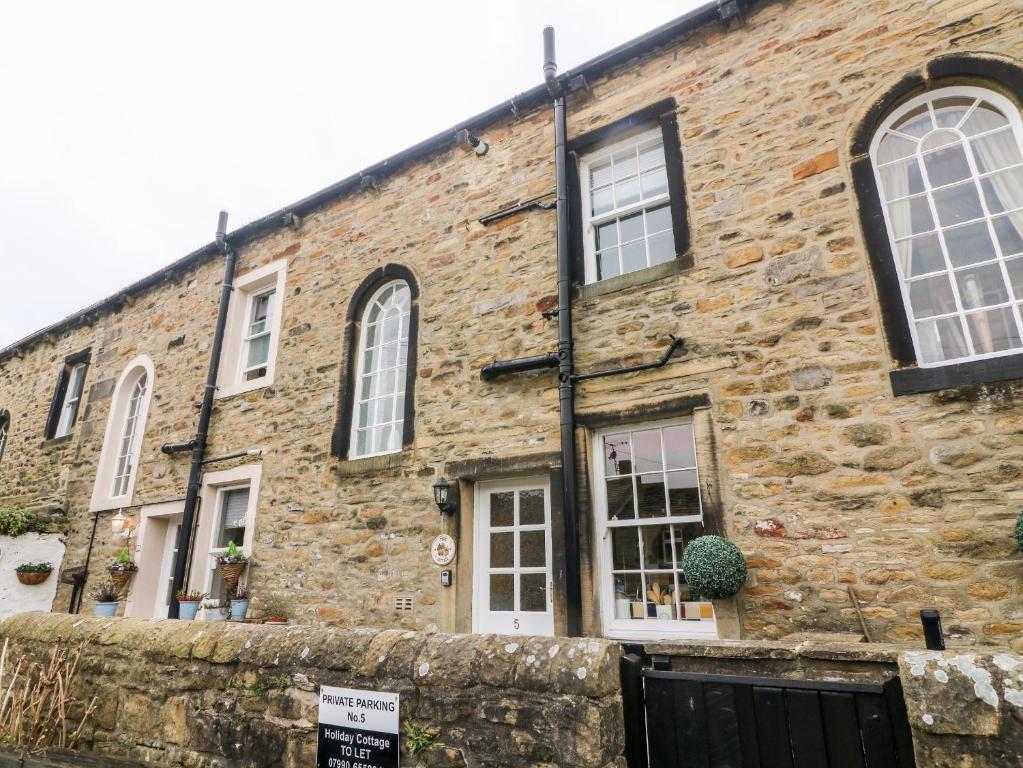 een bakstenen gebouw met witte ramen en een deur bij Town Cottage in Skipton