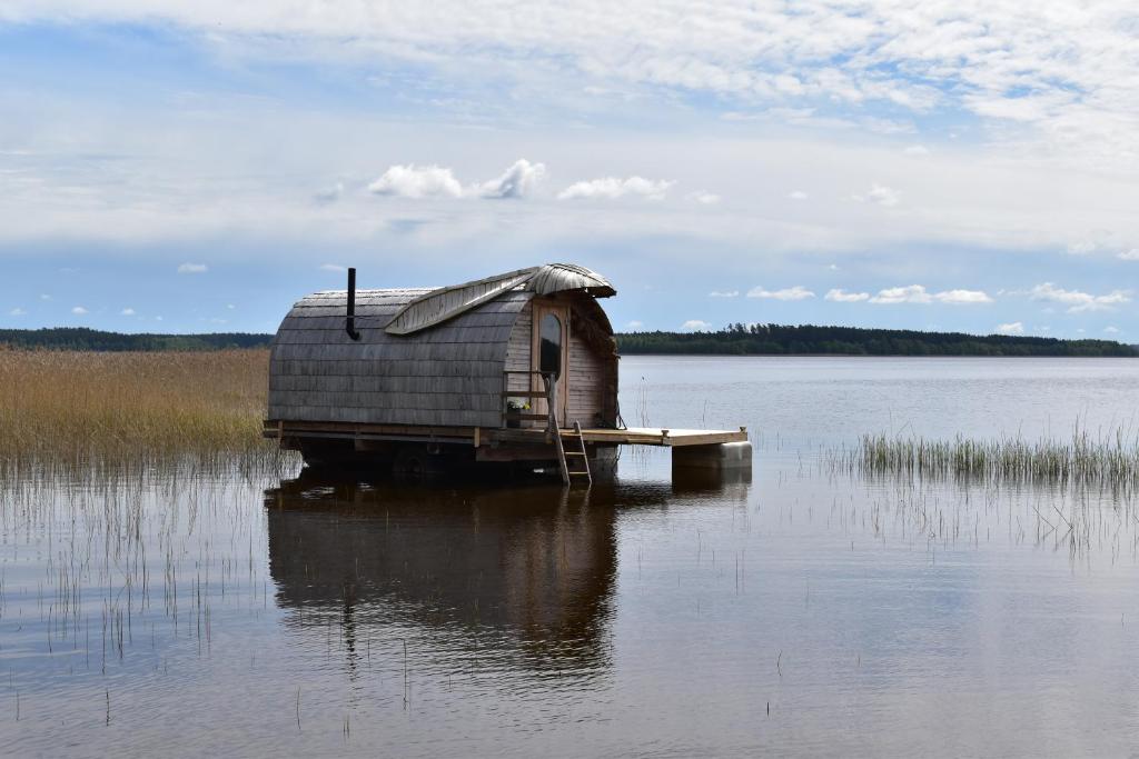 una pequeña casa en un muelle en un cuerpo de agua en Usmas zaķīšu pirtiņa - Bunny house, en Usma