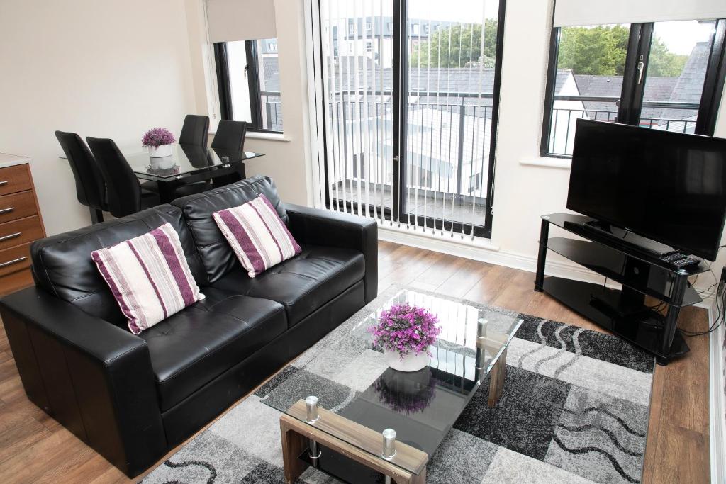 a living room with a black leather couch and a tv at Arch House Apartments in Athlone