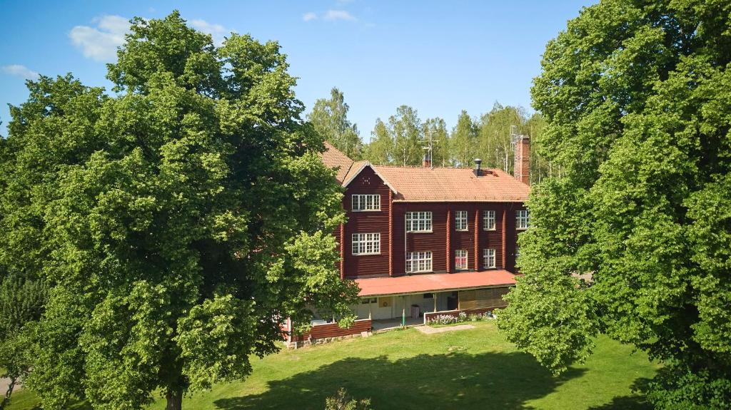 a large red house with trees in front of it at Folkarbo Vandrarhem in Avesta