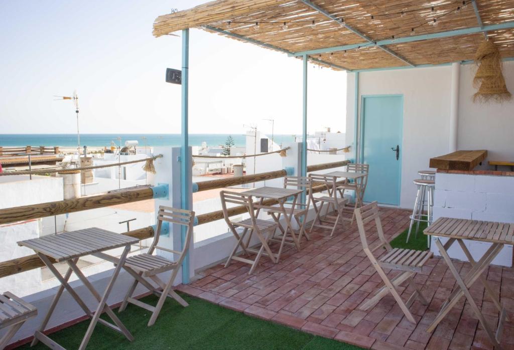 un patio con mesas y sillas y el océano en Salitre Rooms, en Conil de la Frontera