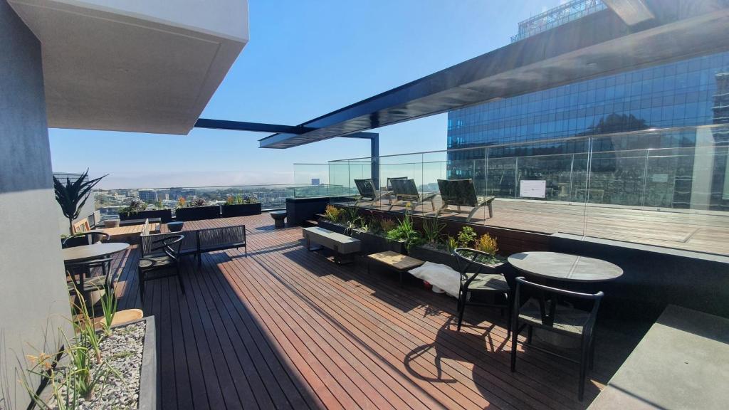 Un balcón con mesas y sillas en un edificio en Always-Power Luxury Sky Retreat, en Ciudad del Cabo