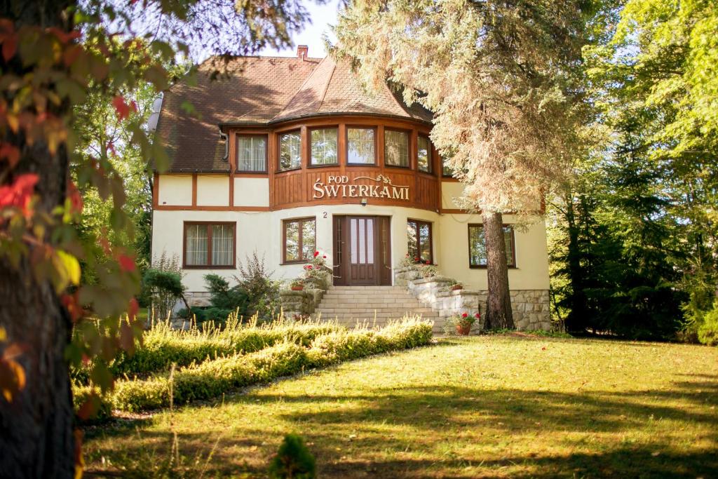 une grande maison avec un arbre en face dans l'établissement Pensjonat Pod Świerkami, à Polanica-Zdrój
