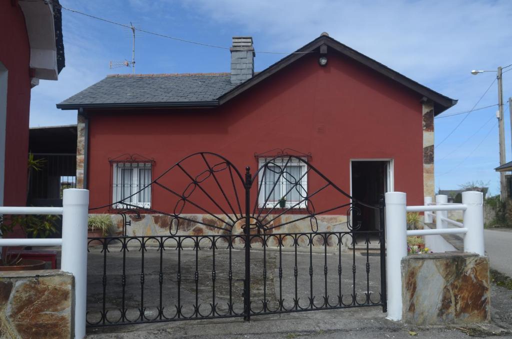 uma casa vermelha com uma cerca em frente em La Casina de Luarca em Luarca