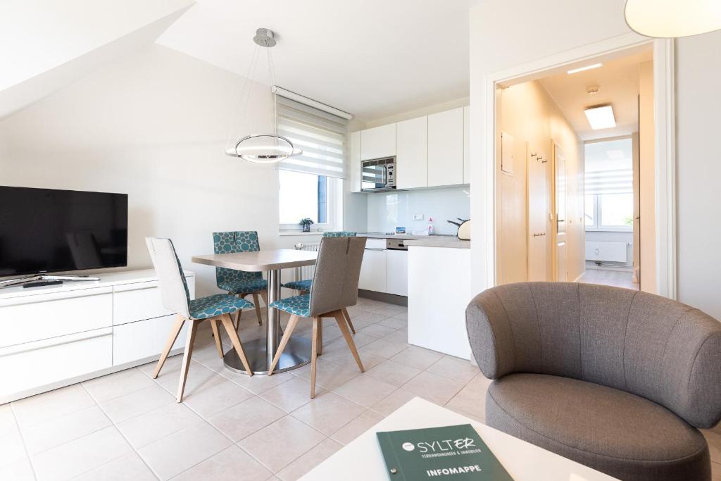 a living room with a table and chairs and a kitchen at Domizil Strandläufer in Wenningstedt