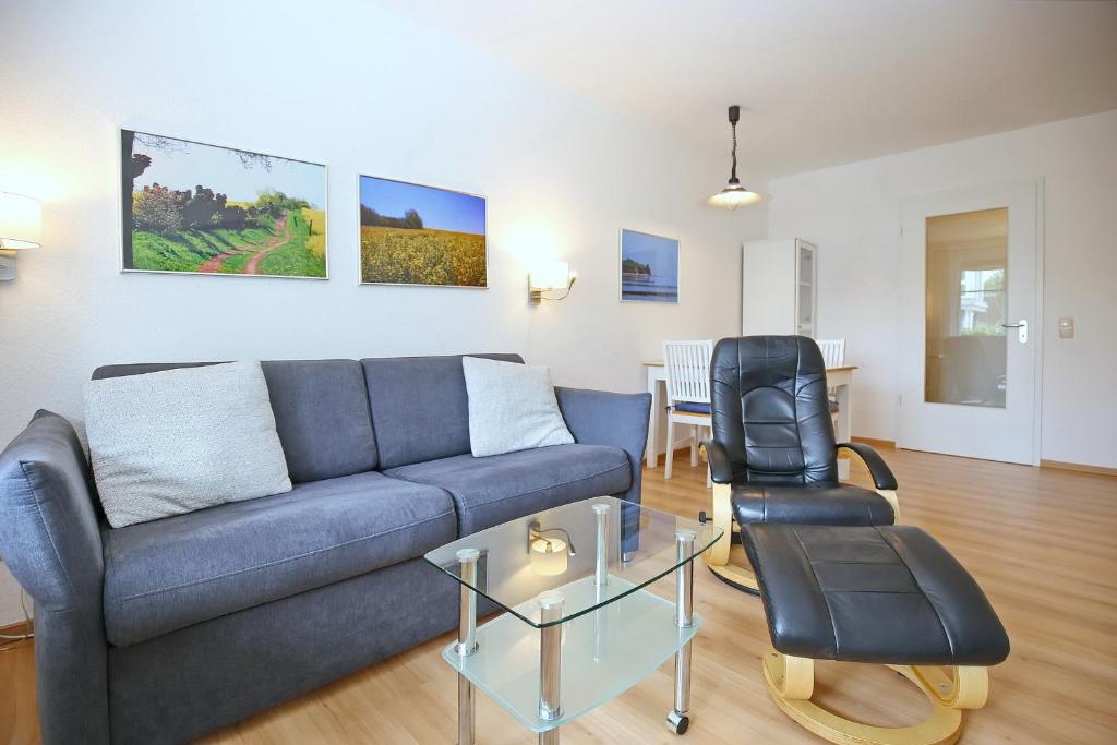 a living room with a blue couch and a glass table at Dünenblick Wohnung 36 in Boltenhagen