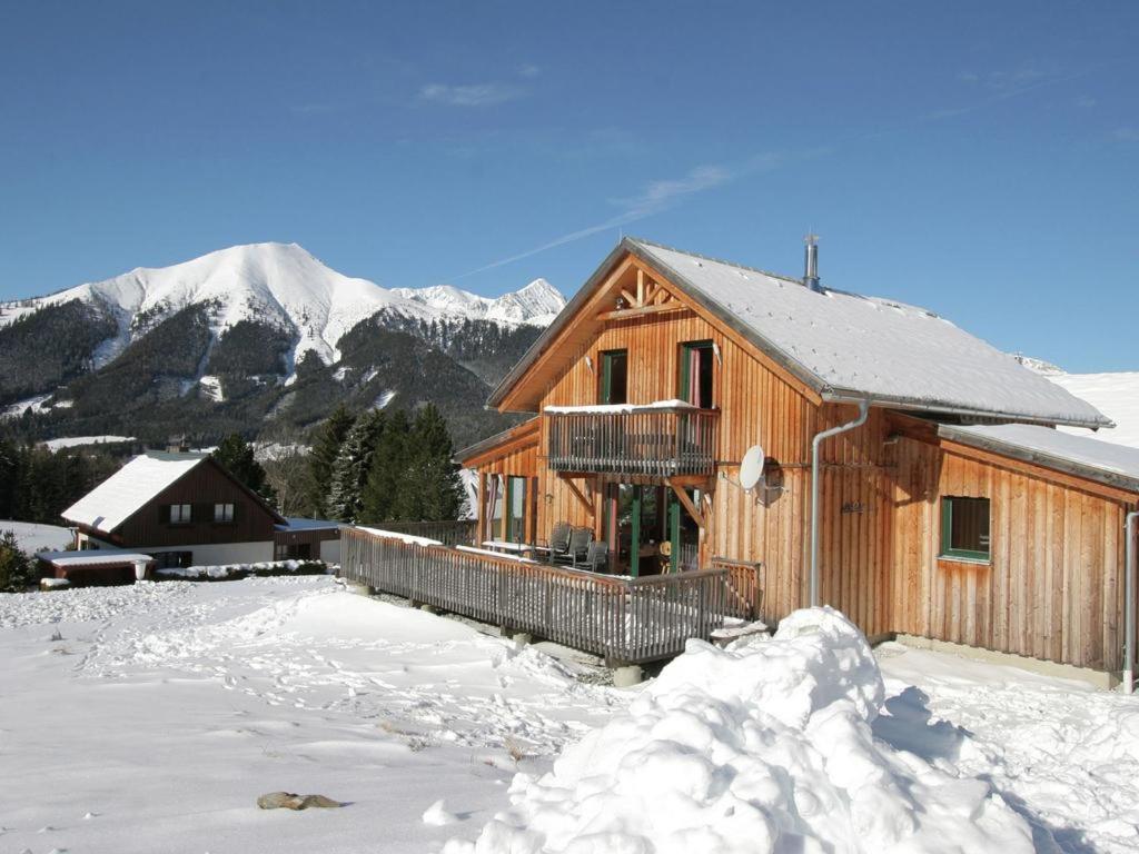 a wooden cabin in the snow with mountains in the background at Auszeit-Hohentauern in Hohentauern