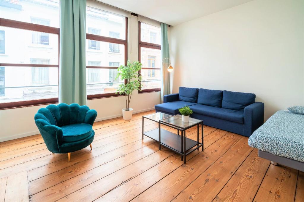 a living room with a blue couch and a table at The Antwerp Old Town Lodge in Antwerp