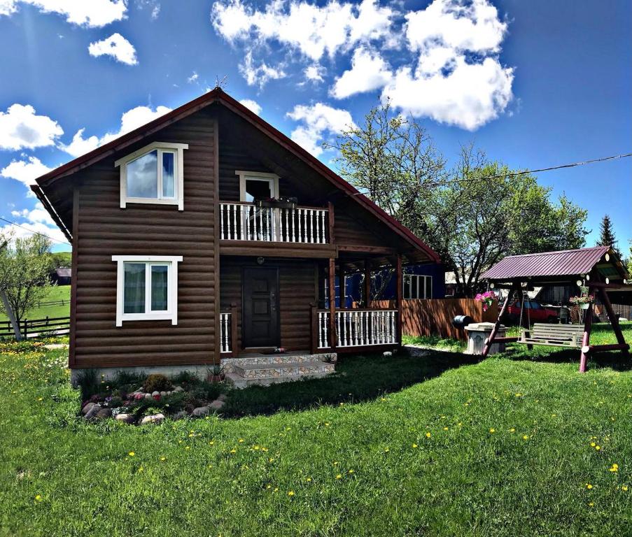 a log house with a balcony and a yard at Приватна садиба "Гірський затишок" in Vorokhta