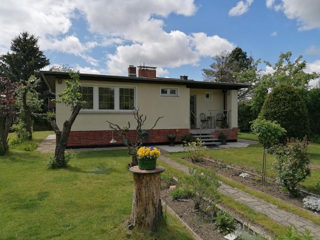 Una casa con un tronco de árbol con una maceta de flores. en Ferienhaus am Rand von Berlin - keine Monteursunterkunft, en Schönefeld